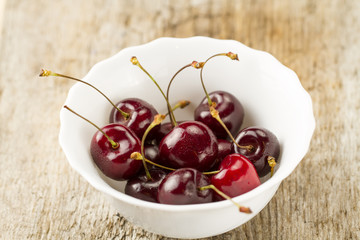 fresh ripe cherry in white plate on wooden background