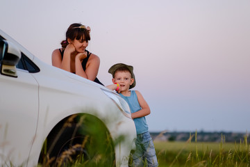 Mother and Son Leaning on Front of the White Car