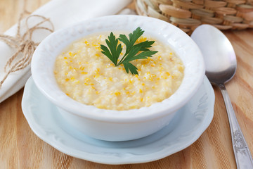 Brazilian corn soup canjiquinha in white vintage plate with fresh corn. Selective focus