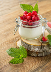 Glass jar with homemade yogurt and fresh garden raspberries