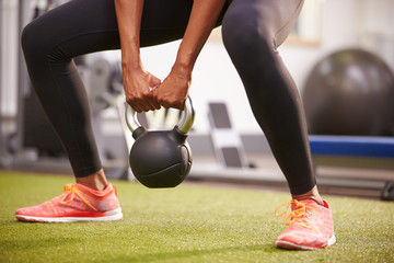 Woman exercising with a kettlebell weight, low-section crop - Powered by Adobe