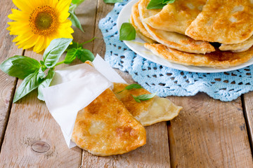 Tasty chebureks with fresh herbs on plate,on wooden background
