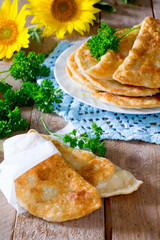 Tasty chebureks with fresh herbs on plate,on wooden background