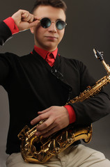 the nice serious young man in a red shirt and a jumper plays a saxophone