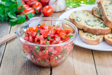 Making tomato bruschetta: garlic cheese crostini and chopped tomatoes with herbs