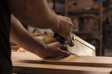 carpenter cutting planks with wood saw