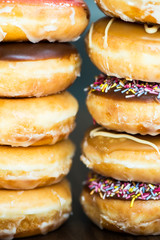 Stacks of Glazed Doughnuts with colourful sprinkles, chocolate,