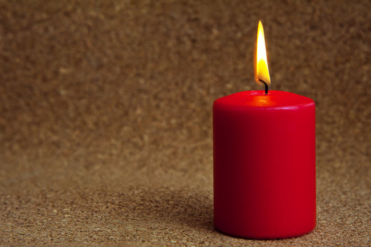Lonely burning red candle on jute background