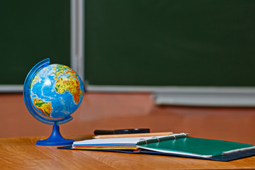 Globe and notebook on the desk in the classroom. School.