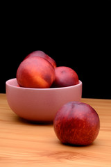 Ripe nectarines are in a plate on a table on a black background