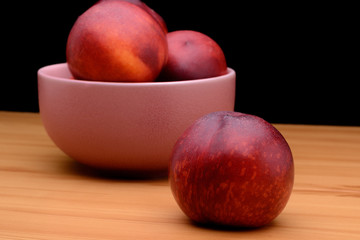 Ripe nectarines are in a plate on a table on a black background