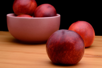 Ripe nectarines are in a plate on a table on a black background