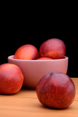 Ripe nectarines are in a plate on a table on a black background