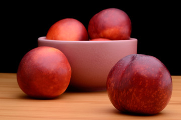 Ripe nectarines are in a plate on a table on a black background