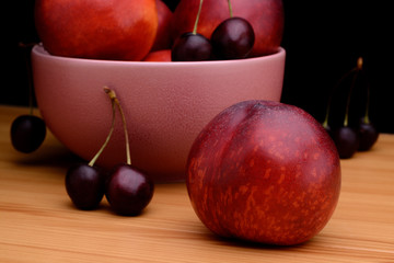Nectarines and cherries on a wooden table on a black background
