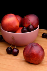 Nectarines and cherries on a wooden table on a black background