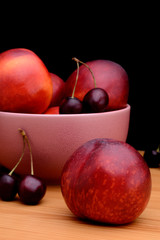 Nectarines and cherries on a wooden table on a black background