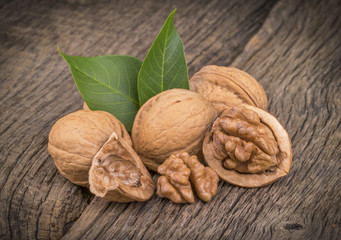 Walnut kernels and whole walnuts on rustic old wooden table