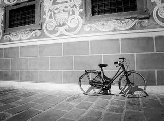 red bike leaning against a wall in black and white