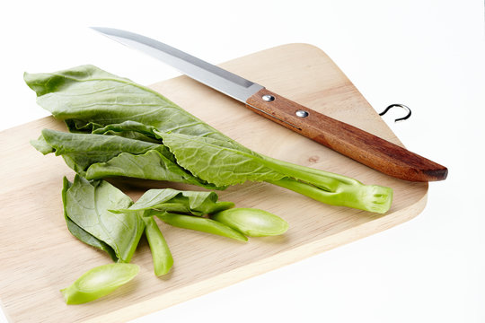 Collard or chinese kale and knift on chopping block isolated on