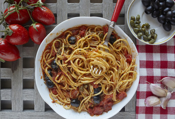 italian food: pasta with tomatoes, olives and capers, called put