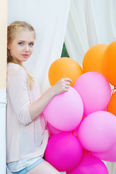 Closeup portrait of beautiful teenager model posing with bright and colorful balloons