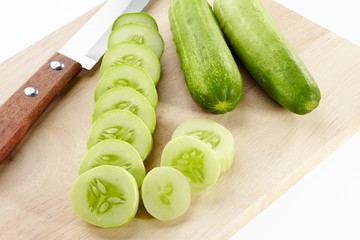 Cucumber, slice cucumber and knife on chopping block isolated on