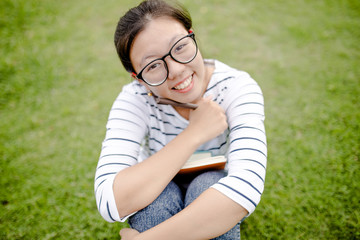A female college student reading a book while lying on the park