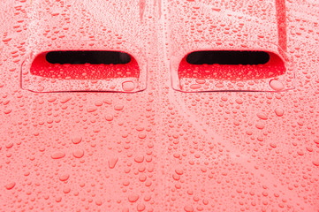 red vehicle panel covered in raindrops
