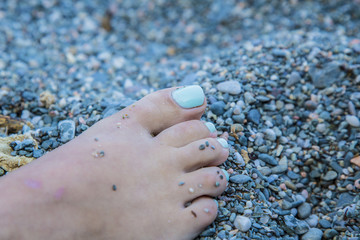Turquoise nails of a women on the sand beach