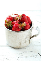 Strawberries berry in cup on white wooden background