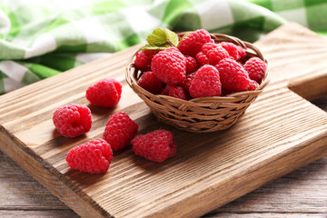 Red raspberries on cutting board on grey wooden background