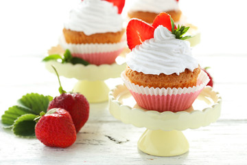Tasty cupcake with strawberry on cake stand on white wooden back