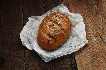 Bread with butter-paper on wooden background