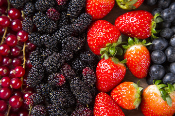 Fototapeta premium Some gooseberries, raspberries, strawberries and blueberries ove