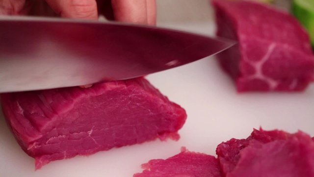 Chef finely slicing beef steak fillet using sharp knife, making beef carpaccio; close up;