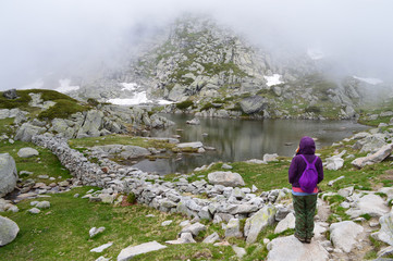 Young woman admiring a mountain lake in fog