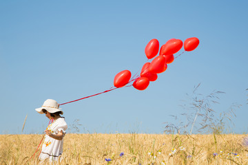 Liebe liegt in der Luft. Kleines Mädchen im Sommer mit roten Herz Luft Ballons 