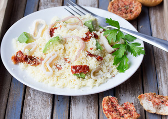 Couscous with seafood, dried tomatoes, avocado and little toast