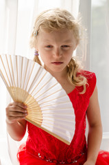 little blond girl in red dress with fan