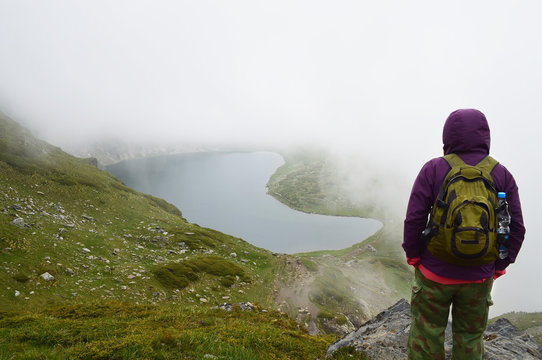 Woman watching hidden in fog mountain lake