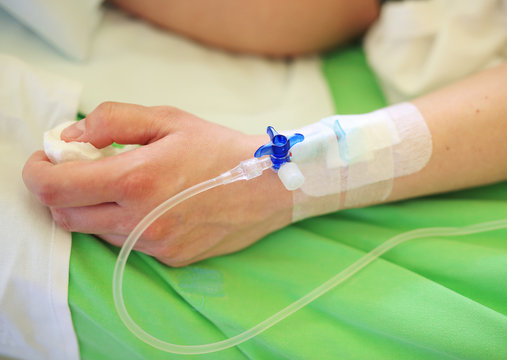 Patient hand with infusion on hospital bed