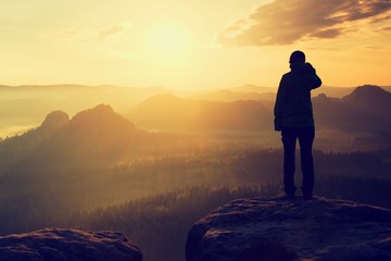 Hiker stand on the sharp corner of sandstone rock in rock empires park and watching over the misty and foggy morning valley to Sun. Beautiful moment the miracle of nature