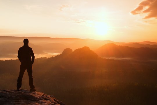Hiker stand on the sharp corner of sandstone rock in rock empires park and watching over the misty and foggy morning valley to Sun. Beautiful moment the miracle of nature