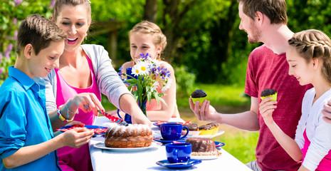 Familie bei Kaffee und Kuchen im Garten vor Haus