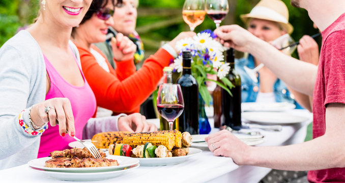 Frau isst Grillwurst auf Gartenparty beim Grillen