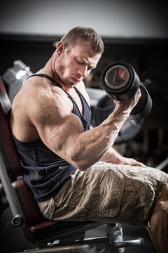 Man at fitness training with dumbbells in gym