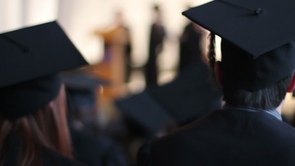 Excited students in caps and gowns applauding at university graduation ceremony