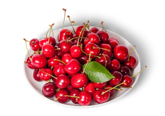 Obraz na płótnie Canvas On top sweet cherries with leaf on white plate