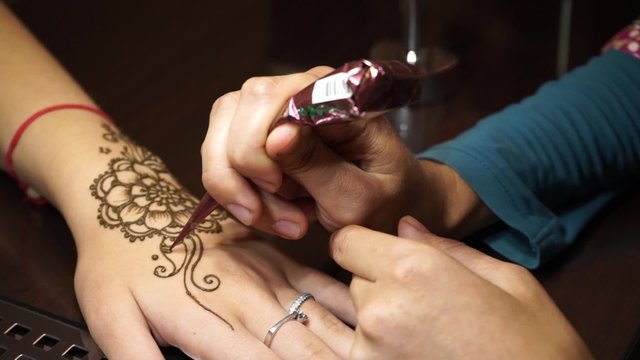 Woman paints henna on her hand